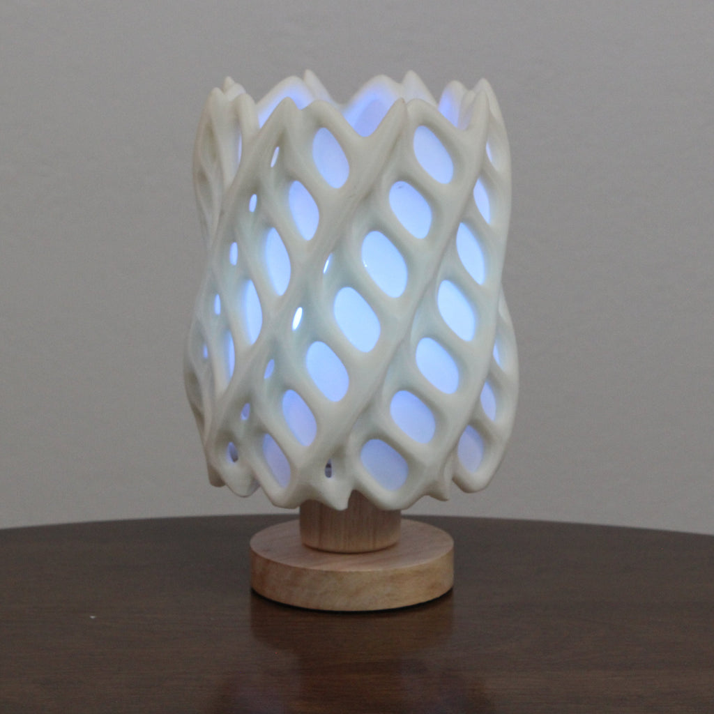 Lattice-patterned ceramic lamp on a wooden base with a white background