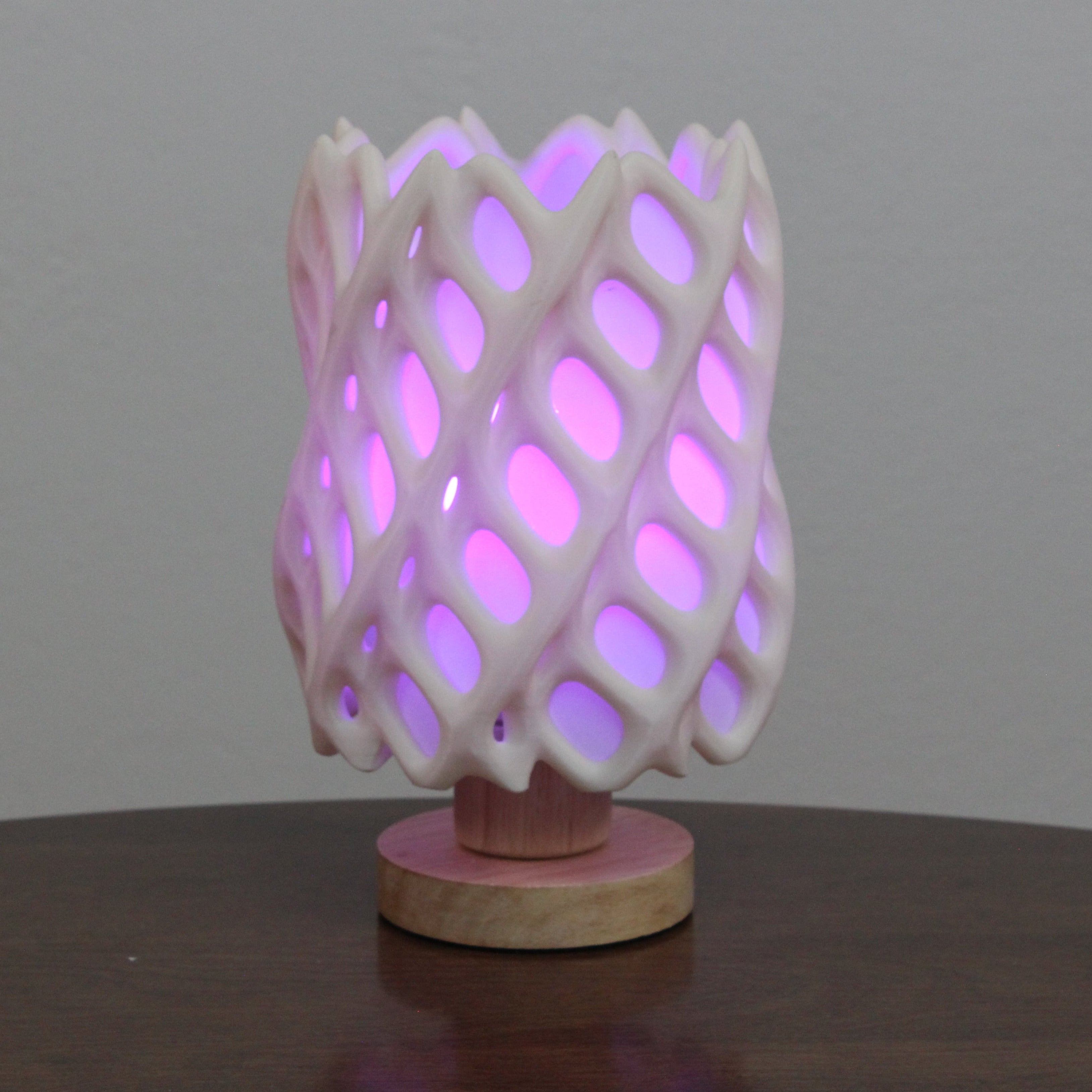 Pink 3D-printed lamp with a geometric design on a wooden base against a gray background, Cholla lamp