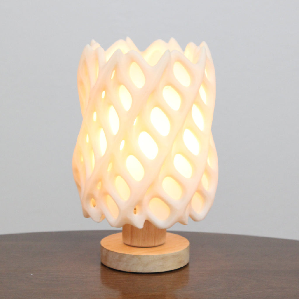 Wooden table lamp with a textured design on a wooden surface and gray background, cholla lamp warm white