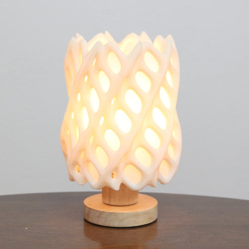 Wooden table lamp with a textured design on a wooden surface and gray background, cholla lamp warm white