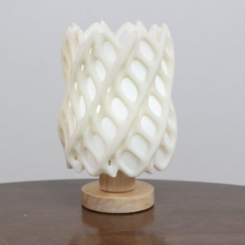 White woven lamp on a wooden base against a gray background