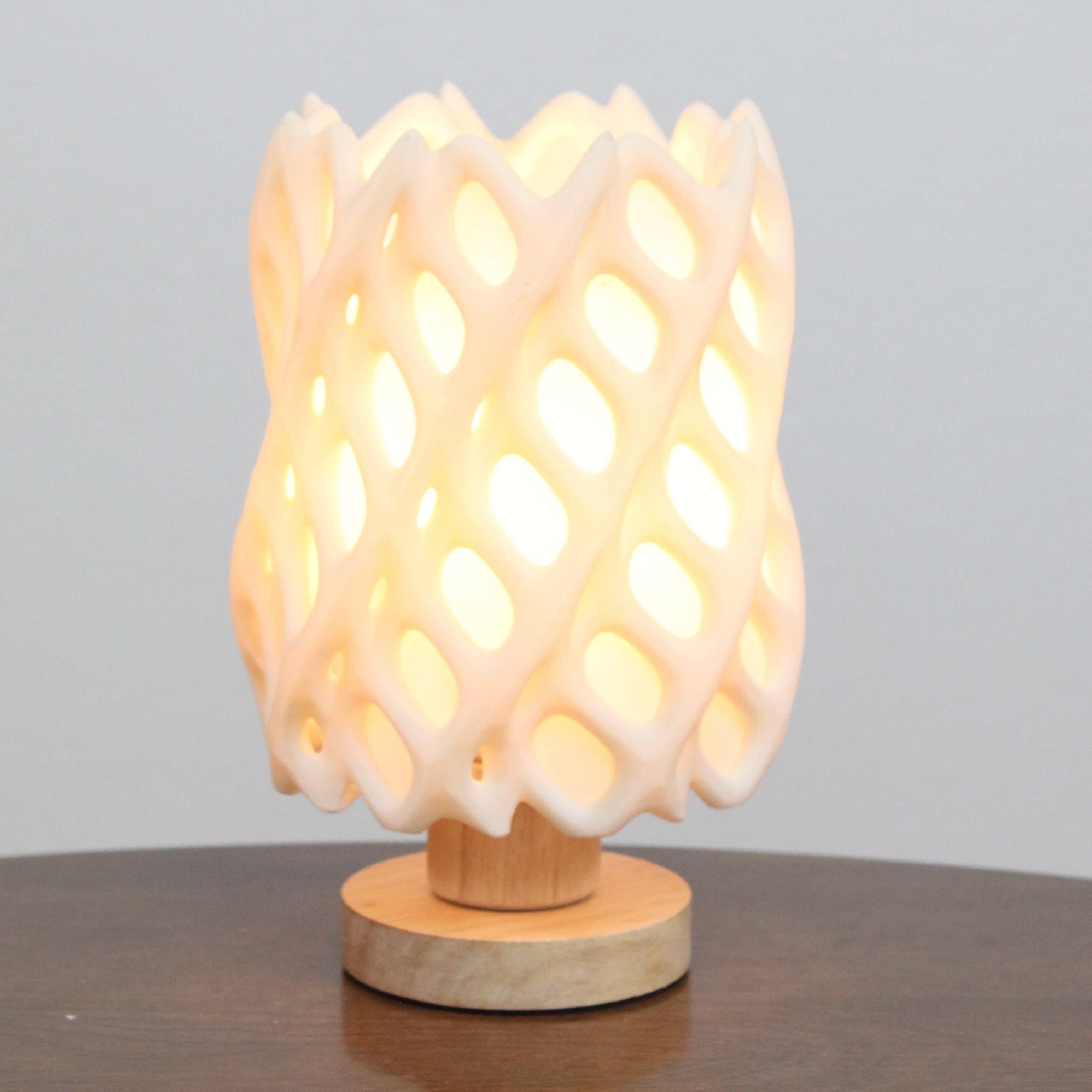Decorative lamp with a textured design on a wooden base against a plain background